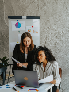 Two women discussing ERP systems on a laptop.