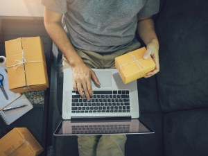 Person working on laptop with shipping packages, representing small business operations with modern software solutions